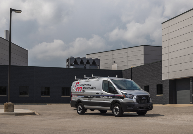 Vehicle in front of building with rooftop unit in background